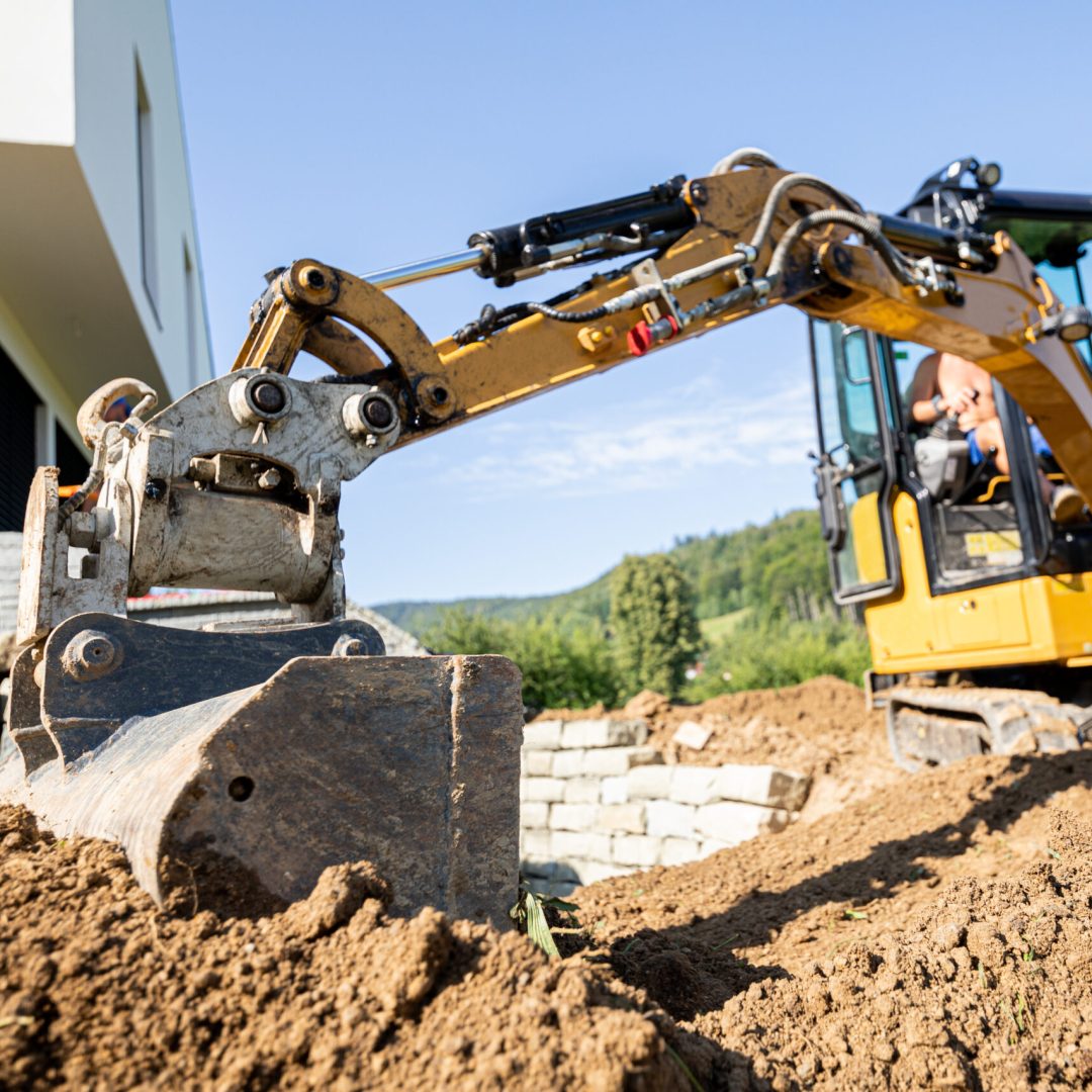 Mini excavator digging preparing ground under home garden